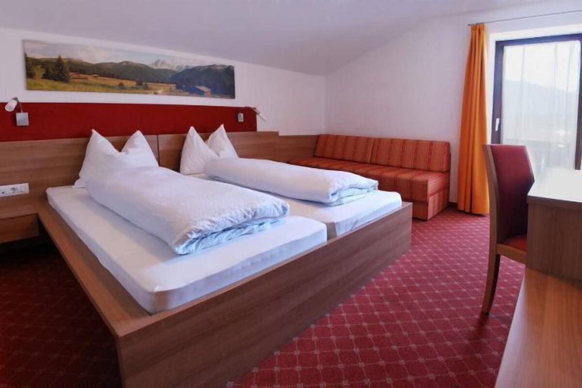 A hotel room with a bed, a desk, and a sofa.