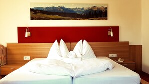 A hotel room with a wooden headboard, a bed with white linens, a painting of mountains, and a red accent wall. - Pension Volgger (Rodengo)