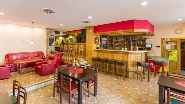 Ein Restaurant mit roten Sitzplätzen, einer Bar und einem gefliesten Boden.