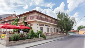Ein Gebäude mit einem Balkon, Außenbereich mit roten Sonnenschirmen und Schildern für "Pension Retro" und "Funhouse".