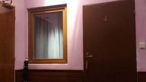Ein Zimmer mit einer einzigen Tür, die mit der Nummer 4 gekennzeichnet ist, einem Fenster mit Vorhang und einem Holzschrank.