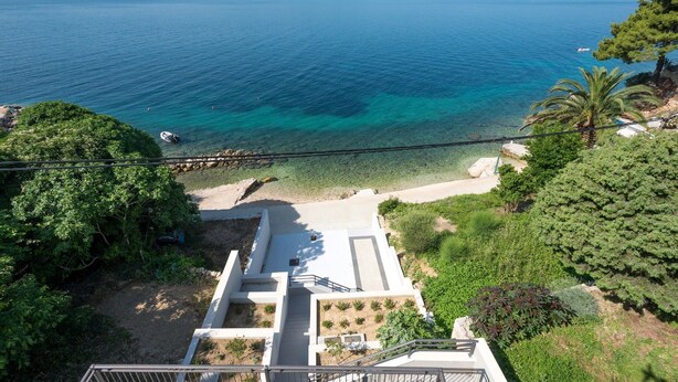 Une vue sur la côte, avec une eau cristalline, une plage et un escalier descendant vers le rivage.