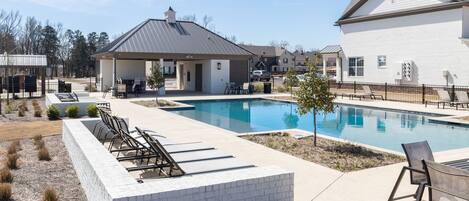 A residential area with a swimming pool, outdoor seating, and a covered patio.