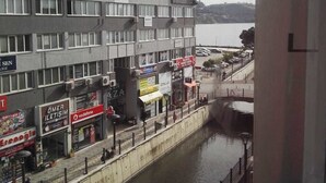 En høj bygning med mange vinduer og altaner, en fodgængerbro og en kanal i forgrunden.