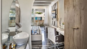 Une salle de bain moderne avec une baignoire sur pieds, un grand miroir et un meuble-lavabo doté d’un plan de travail en marbre.