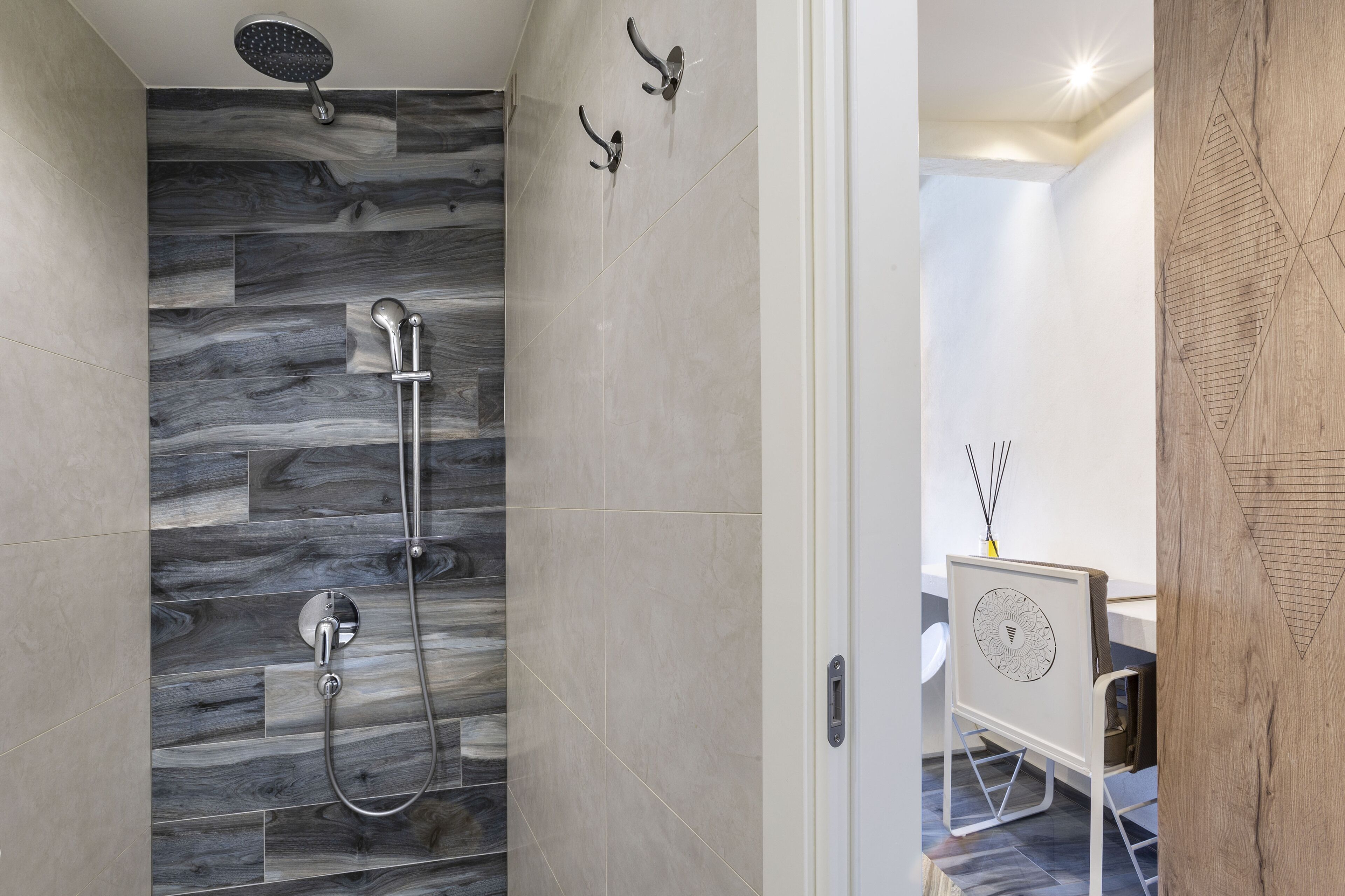 Un baño moderno con ducha, tocador con espejo y una pared decorativa de madera.