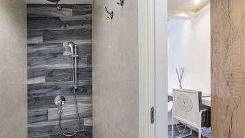 Un baño moderno con ducha, tocador con espejo y una pared decorativa de madera.
