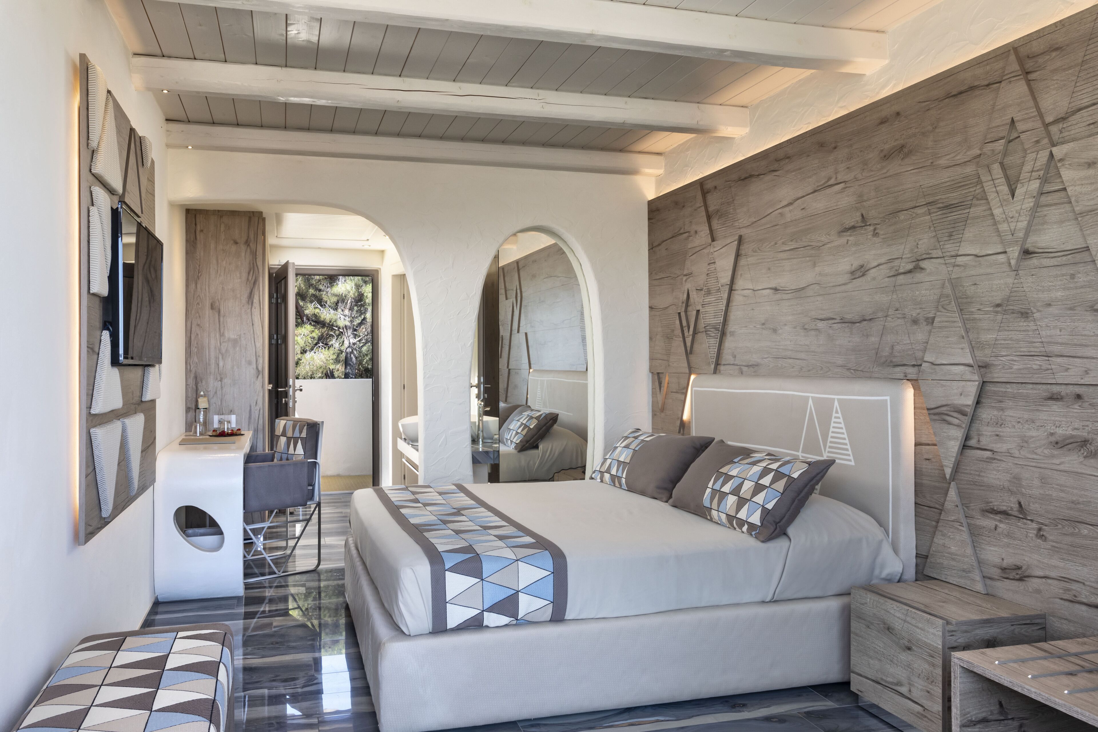 A modern bedroom with a large bed, a TV, and a wooden accent wall.