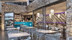 Un restaurant moderne avec des murs en pierre, des portes en verre et des chaises en osier.