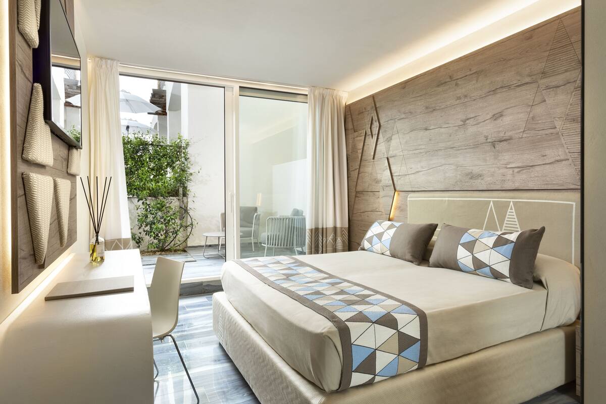 Habitación de hotel moderna con una cama grande, un escritorio y vistas al exterior.
