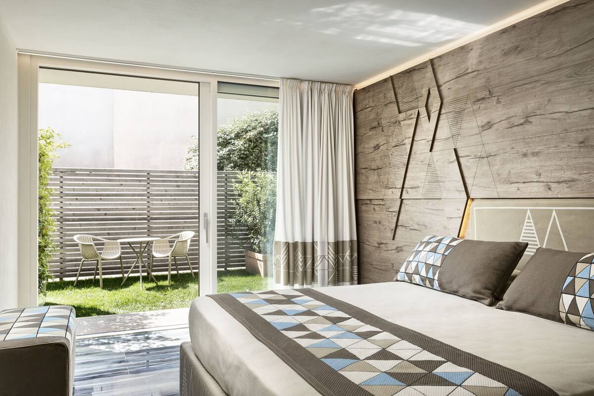 Un dormitorio moderno con una cama grande, vistas al exterior y un cabecero de madera.