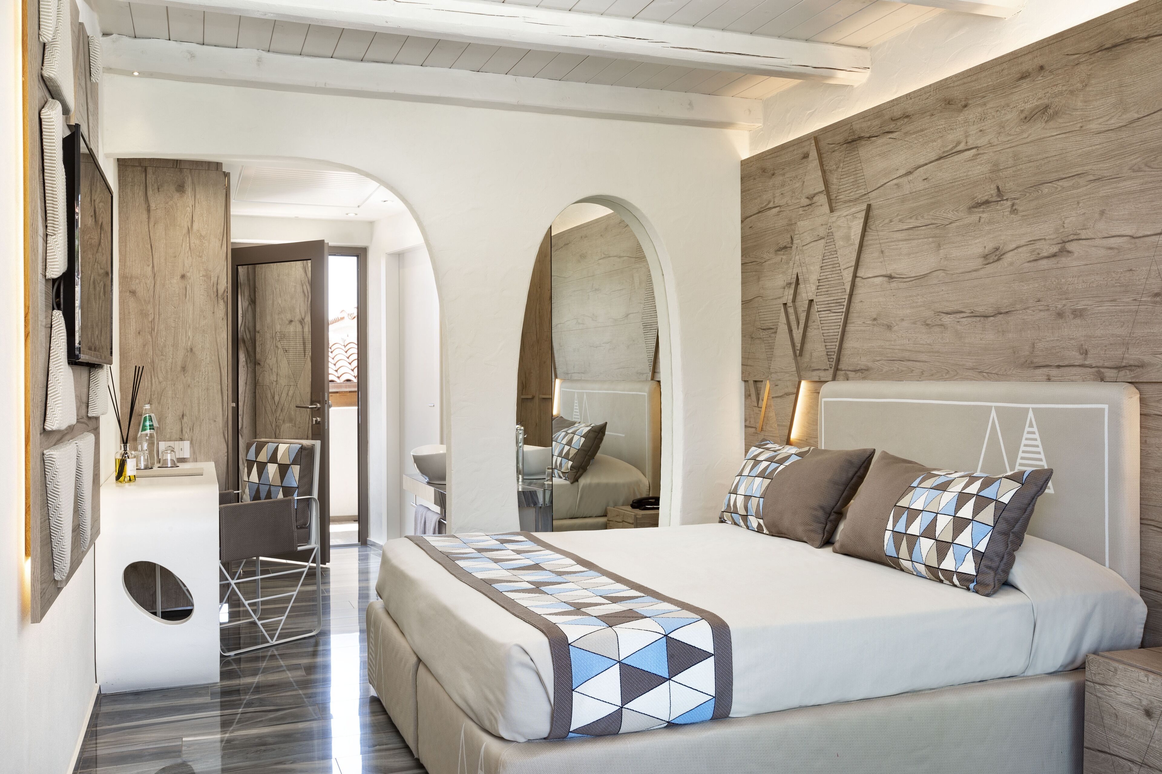 A modern bedroom with a large bed, a wooden headboard, and a built-in desk with a chair.