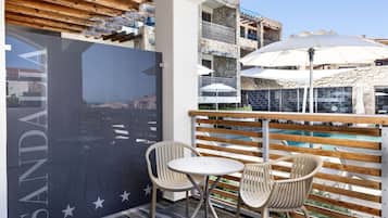 A balcony with a view of a pool, two white chairs, and a table.