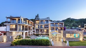 Un hôtel à plusieurs étages doté d’une piscine, d’un espace extérieur aménagé et d’une façade en pierre.