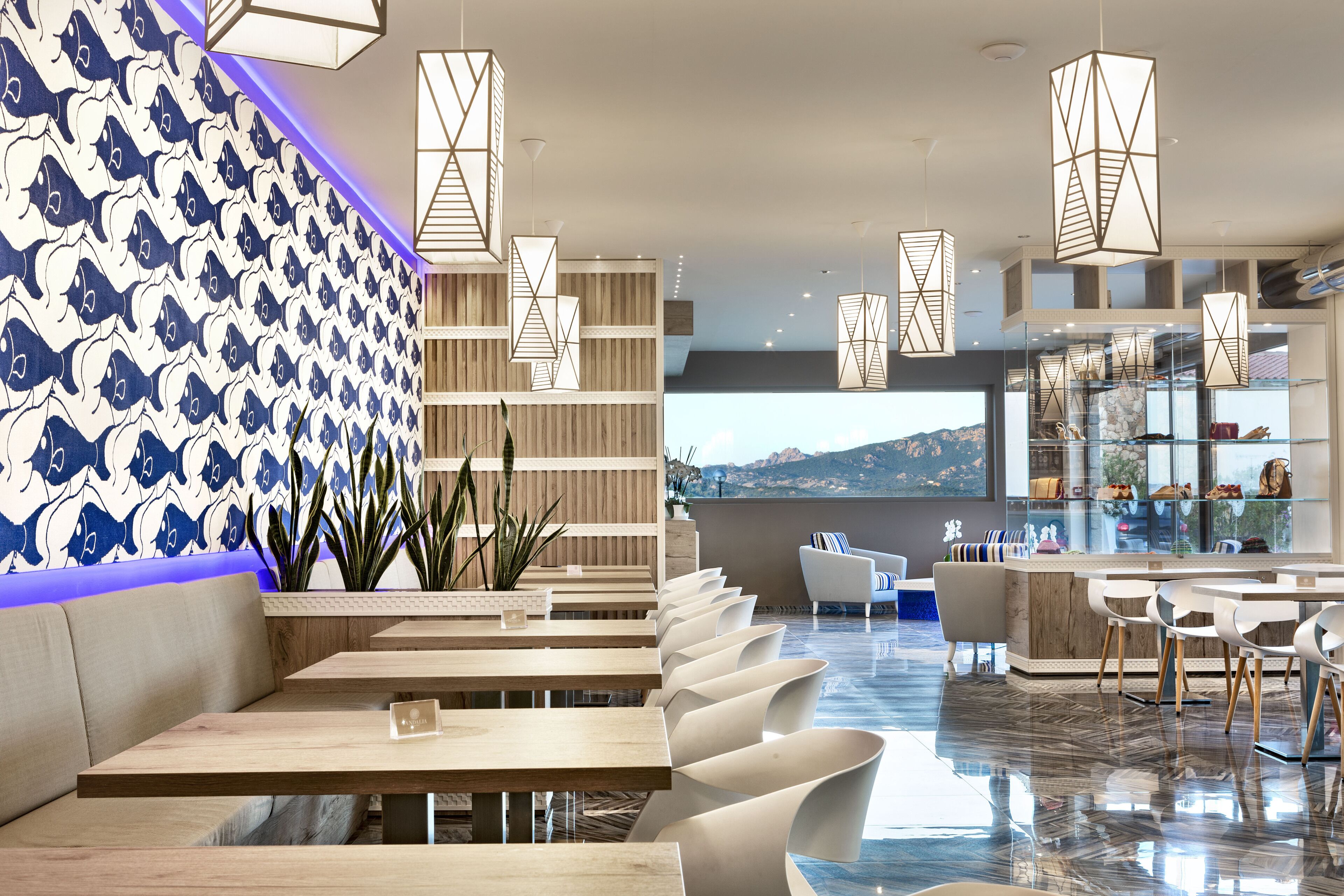 A modern restaurant with wooden tables and chairs, a patterned wall, and hanging light fixtures.