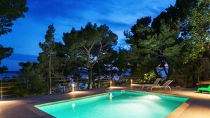 A rectangular swimming pool with a tiled edge, surrounded by a deck with lounge chairs. - Villa Zorana (Brela)