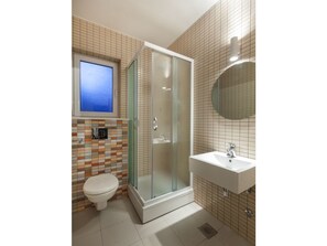 A modern bathroom with a glass-enclosed shower, a toilet, and a sink with a mirror.