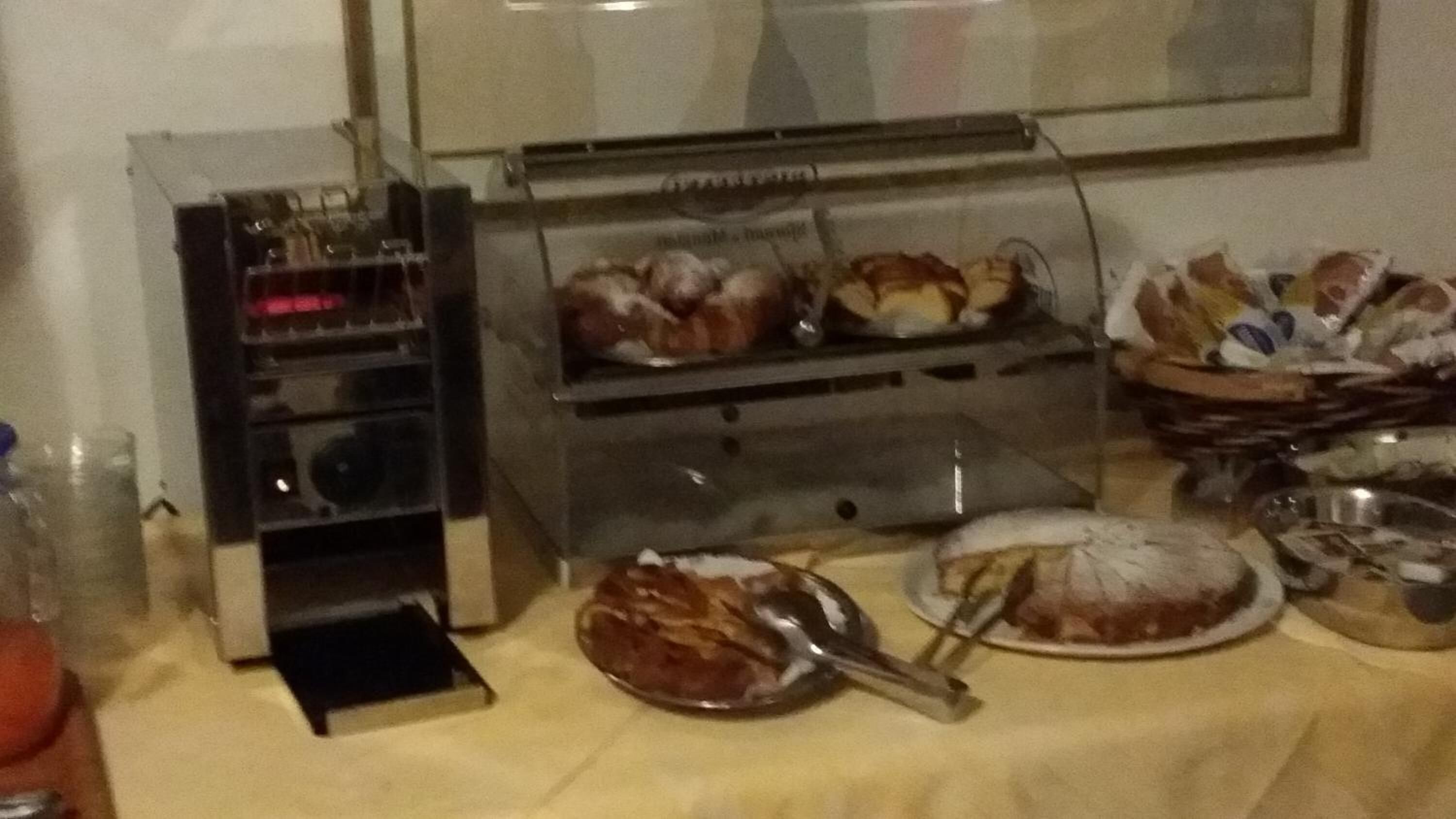 A buffet setup with various food items, including a cake and a pie, on a table with a yellow tablecloth.