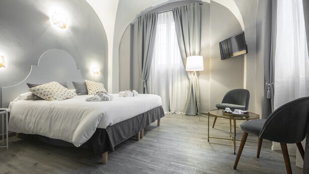 Una habitación de hotel moderna con una cama grande, un escritorio, una silla y un televisor montado en la pared.