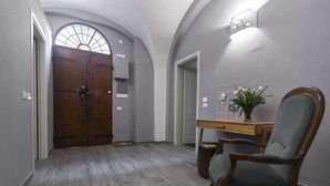 Un pasillo con una puerta de madera, un escritorio con un florero y una silla.