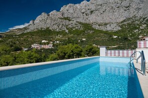 Una piscina al aire libre, sombrillas, sillones reclinables de piscina