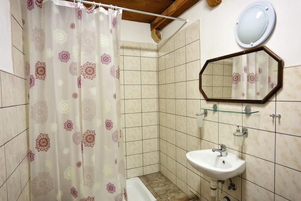 Un baño con cortina de ducha, lavamanos y espejo.