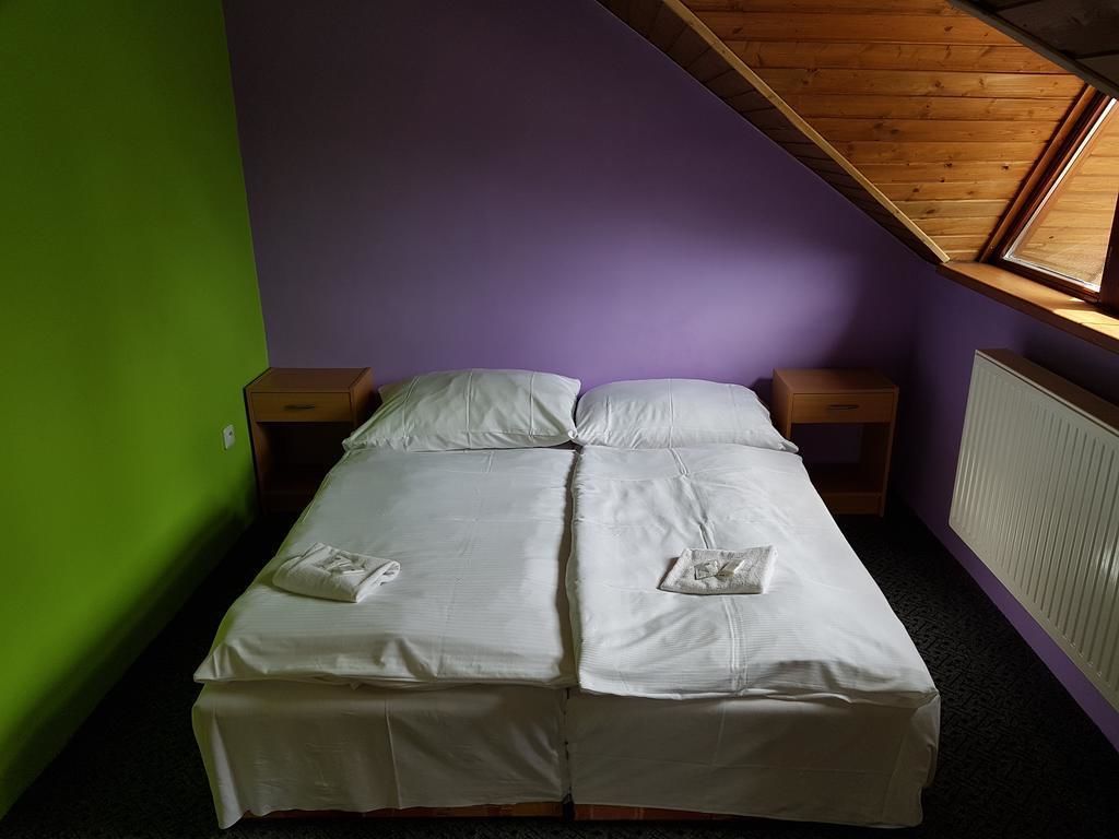 A twin bed with white linens, two bedside tables, a window with wooden beams, and a radiator on the wall.
