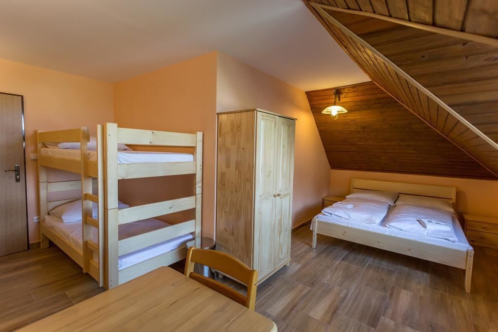 Un dormitorio con literas, un armario, una mesa y un techo de vigas de madera.