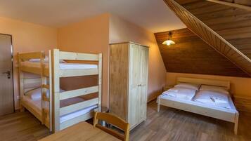 Un dormitorio con literas, un armario, una mesa y un techo de vigas de madera.