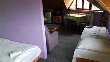 A small, cozy room with two beds, a table, and a chair.