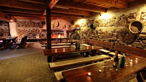 Un interior rústico con paredes de piedra, bancos de madera y una chimenea.