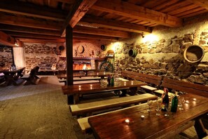 A rustic interior with stone walls, wooden benches, and a fireplace. - Penzion Šatovské Lípy (Šatov)