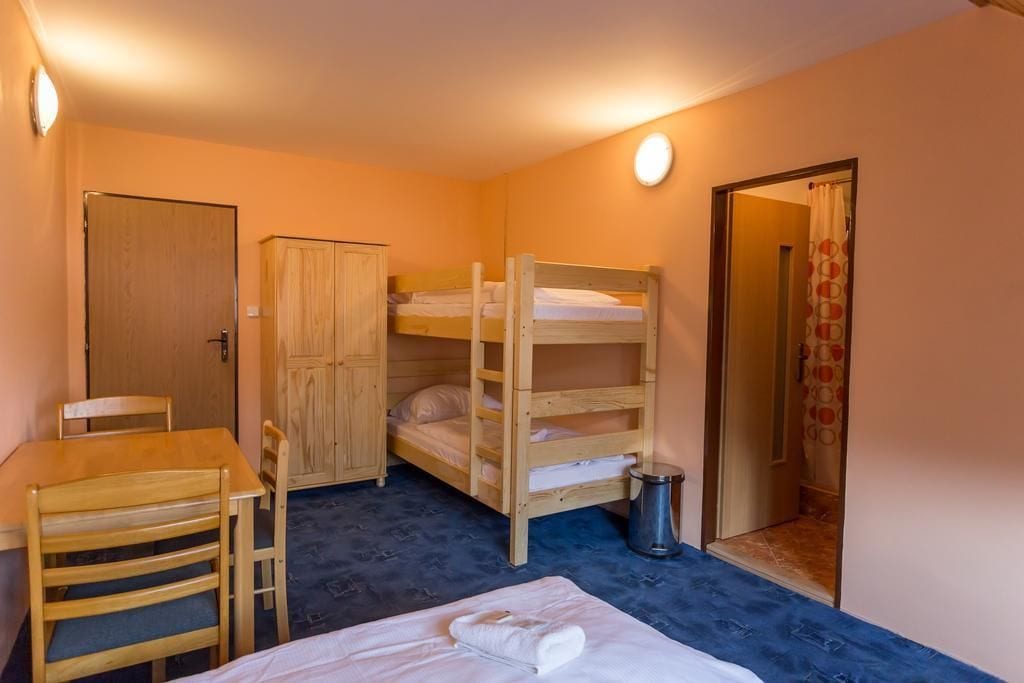 Ein kleiner, gemütlicher Raum mit Etagenbetten, einem Holztisch, einem Stuhl und einem Schrank.