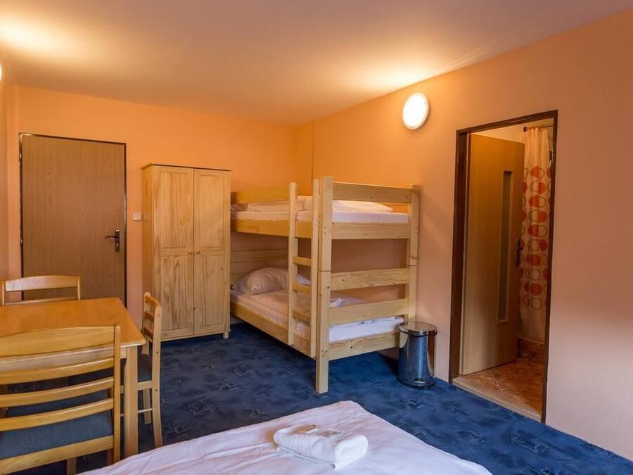Una habitació petita i acollidora amb literes, un escriptori de fusta, una cadira i un armari.