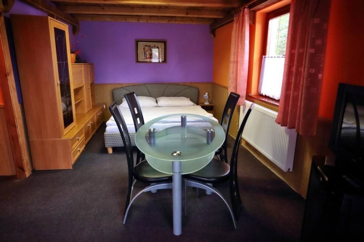 Une pièce comprenant un lit, une table en verre avec des chaises, une armoire en bois et une fenêtre avec des rideaux.