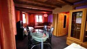 Una habitación acogedora con mesa de comedor de cristal, armarios de madera y un rincón de estar cómodo.