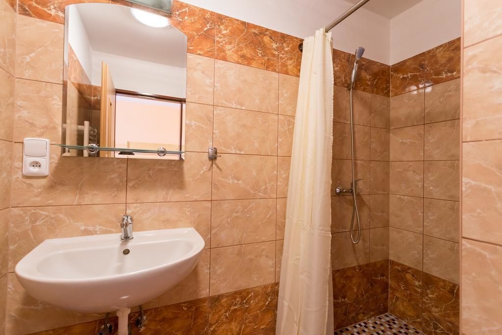 Un baño con lavamanos, espejo, ducha y paredes de azulejos.