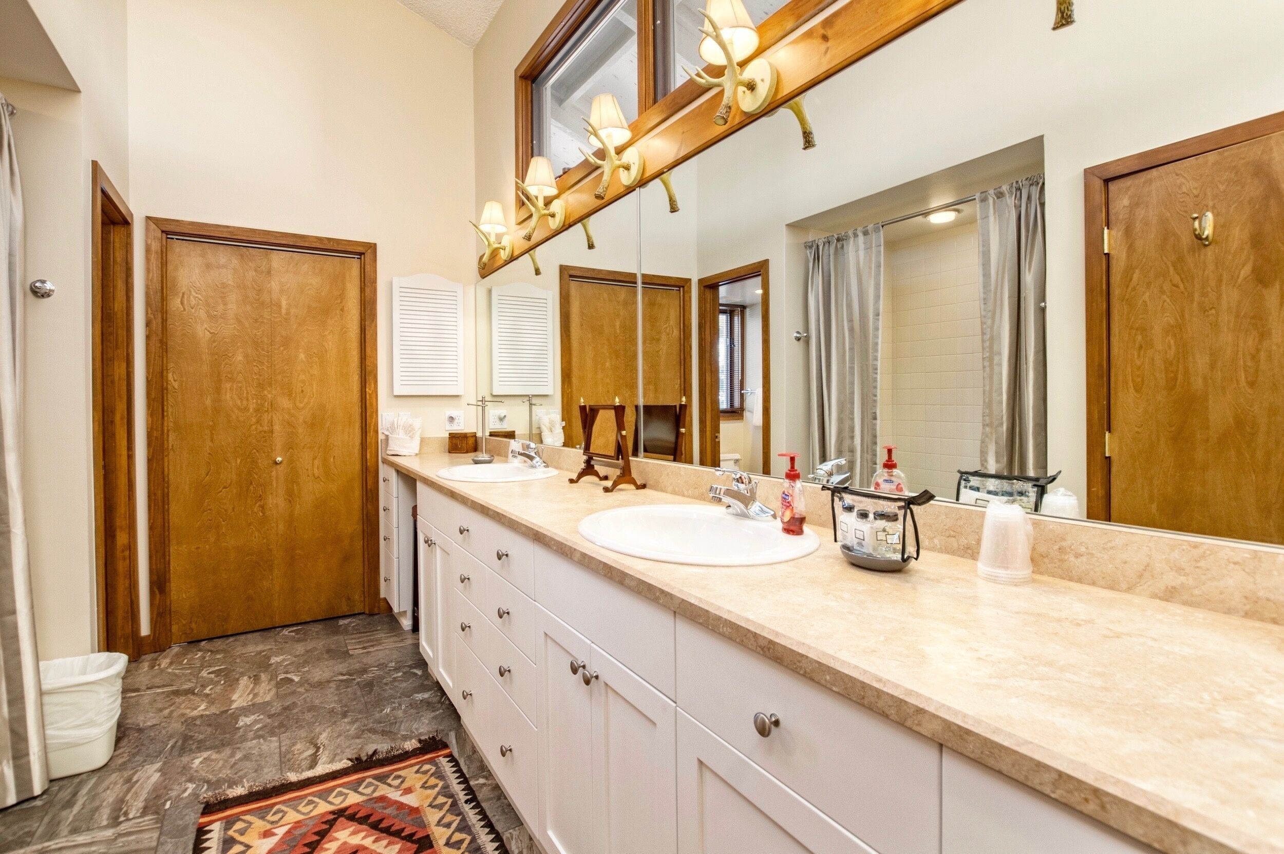 Une salle de bain avec deux lavabos, un grand miroir et un meuble-lavabo en bois.