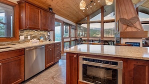 A modern kitchen with wooden cabinets, a large island, and a view of the mountains. - Herondale Luxury Vacation  At Windcliff 3 Bedroom Home by RedAwning (Estes Park)