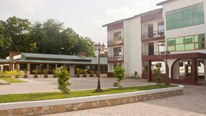Un hotel de varios pisos con un patio central, zona de estar al aire libre y un jardín bien cuidado.