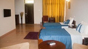 Una habitación de hotel con dos camas, televisión, escritorio y una silla.
