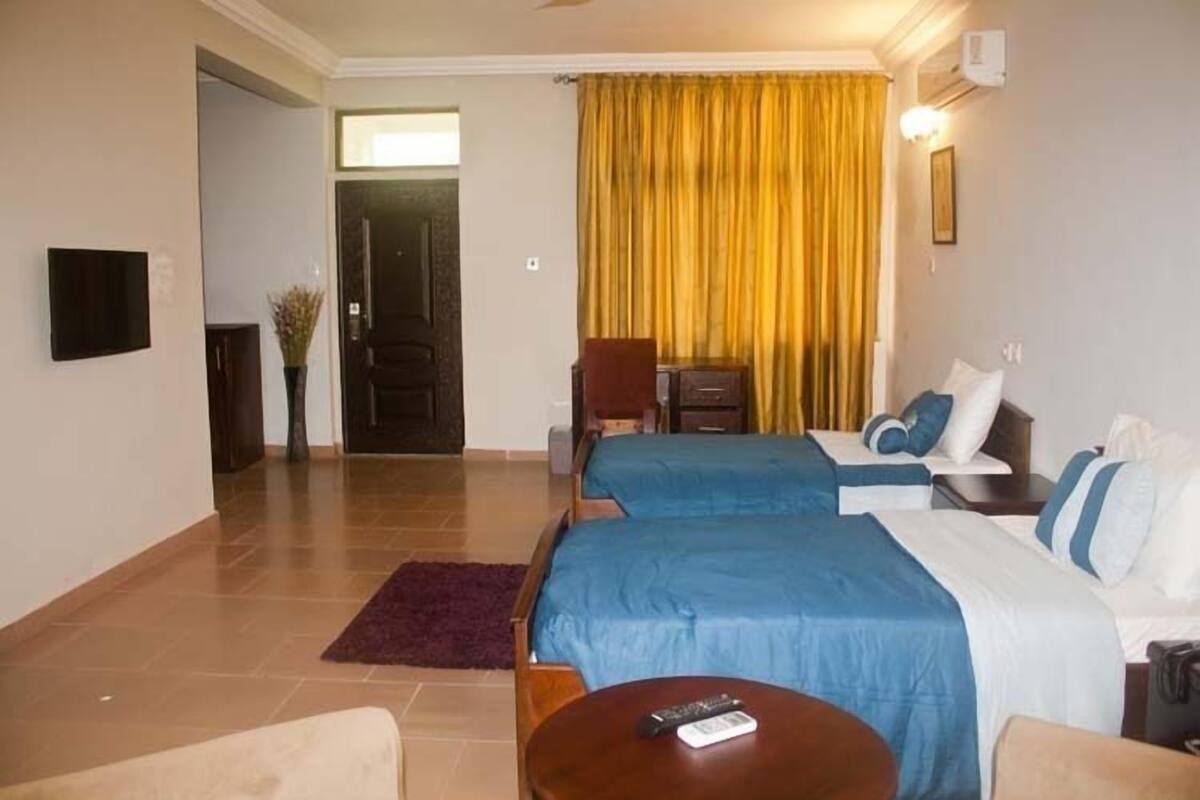 A hotel room with two beds, a TV, a desk, and a chair.