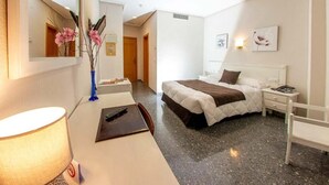 A hotel room with a bed, bedside table, lamp, and a mirror. - Hospedium Hotel Don José (Castalla)