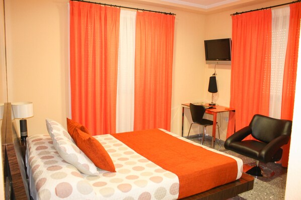 A hotel room with a bed, a desk, a chair, and a television.