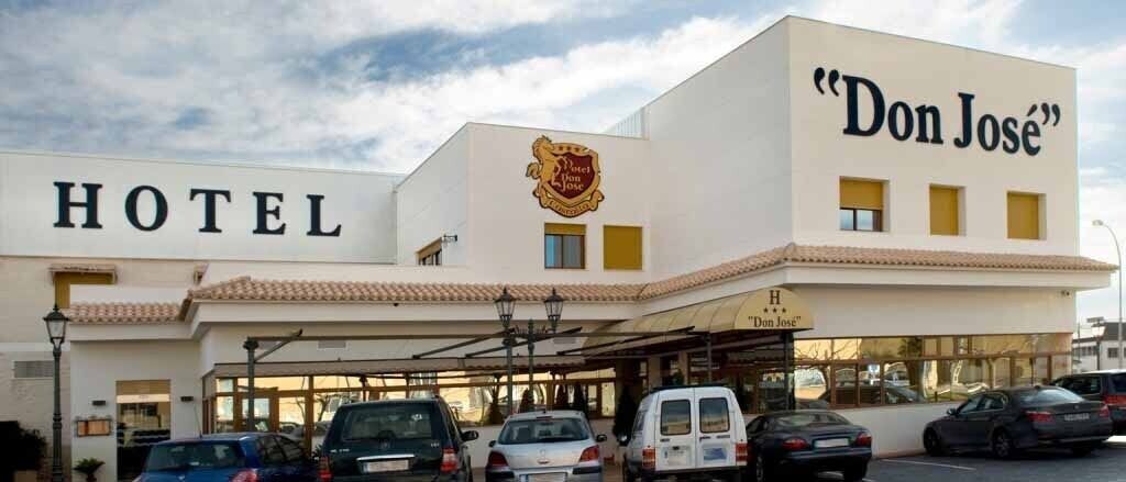 A hotel named "Don José" with a prominent sign and a parking area in front.