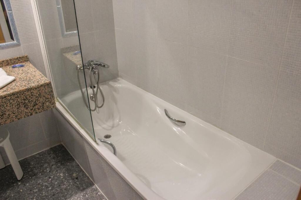 A bathroom with a white bathtub, a glass shower enclosure, and a granite countertop.