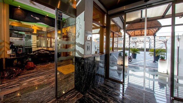 A modern hotel lobby with a marble floor, glass doors leading to a dining area, and a view of the street outside. - Hospedium Hotel Don José (Castalla)