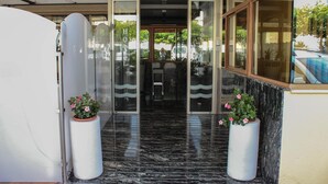 A hotel entrance with glass doors, a marble floor, and potted plants. - Hospedium Hotel Don José (Castalla)