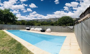 Una piscina al aire libre, sombrillas, sillones reclinables de piscina