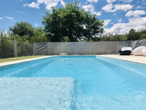 Una piscina al aire libre, sombrillas, sillones reclinables de piscina